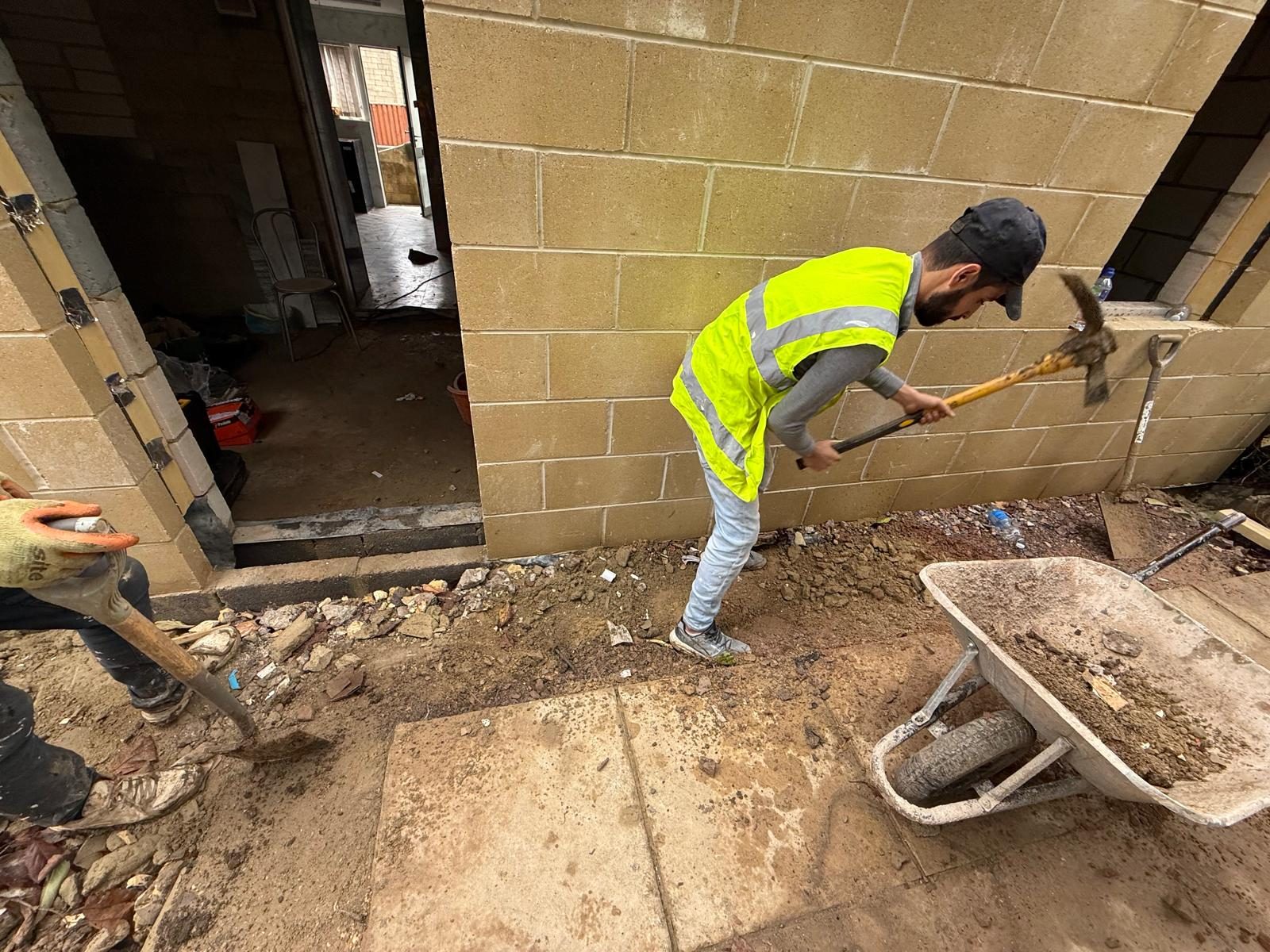 Builder in hi-vis shovelling during groundworks